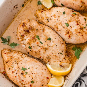 baked italian dressing chicken in a baking sheet garnished with lemon wedges.