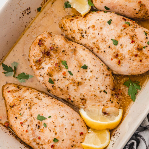 baked italian dressing chicken in a baking sheet garnished with lemon wedges.