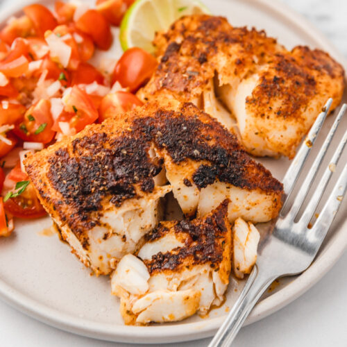 a plate of two blackened cod fillets and pico de gallo.