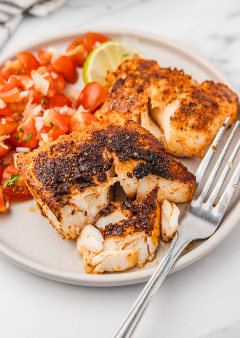a plate of two blackened cod fillets and pico de gallo.