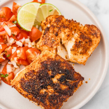 two blackened cod fillets with a side of pico de gallo ona plate.