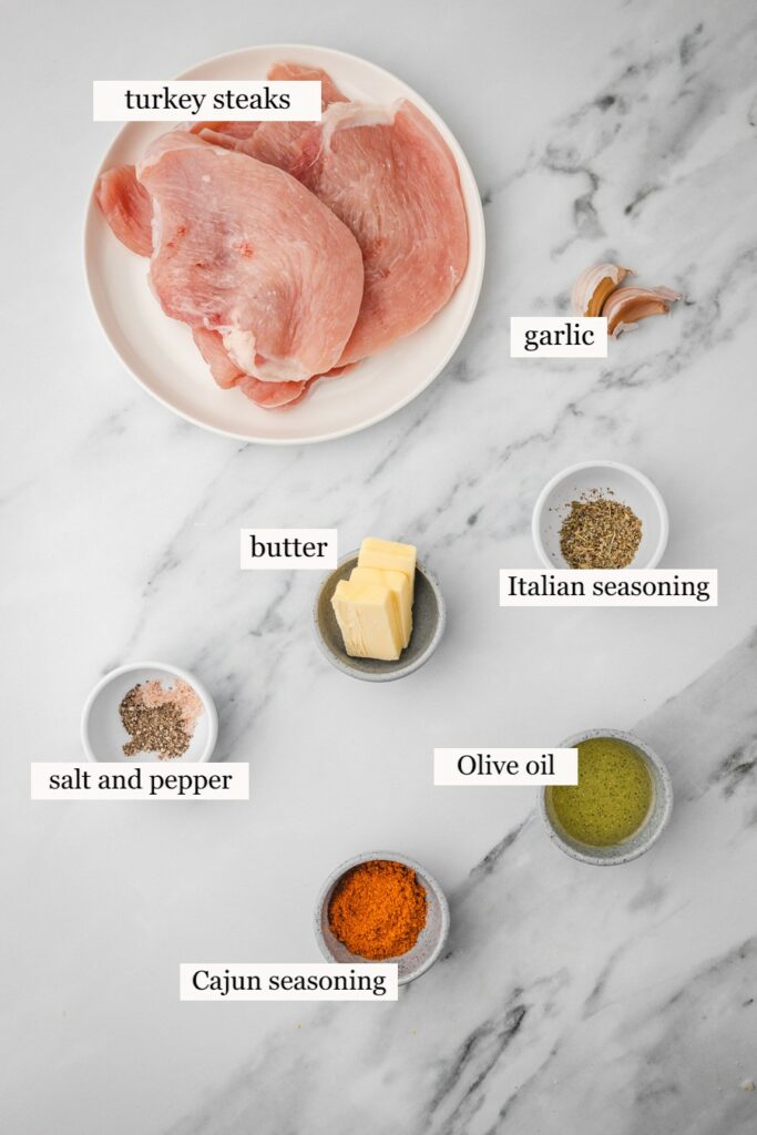 ingredients needed to cook turkey steaks placed on a white marble surface.