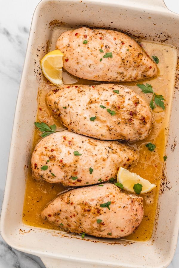 four baked chicken breast in baking dish.
