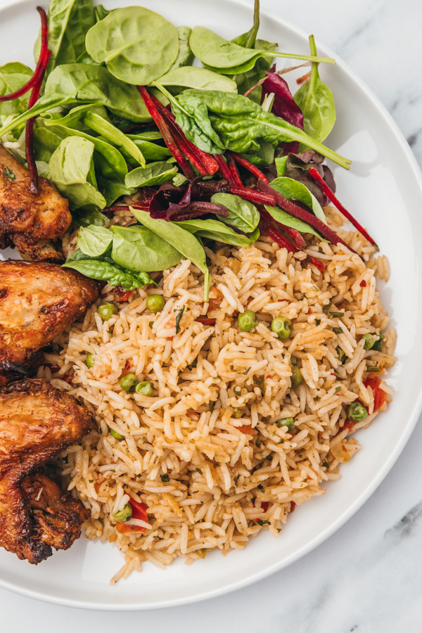 a plate of rice, salad and chicken wings.