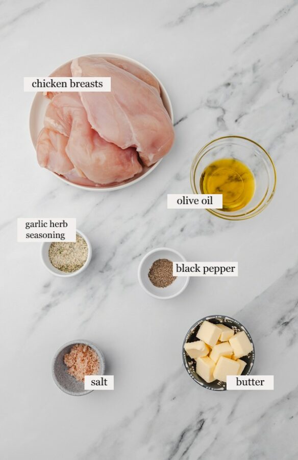 ingredients to make garlic herb chicken on a marble surface.