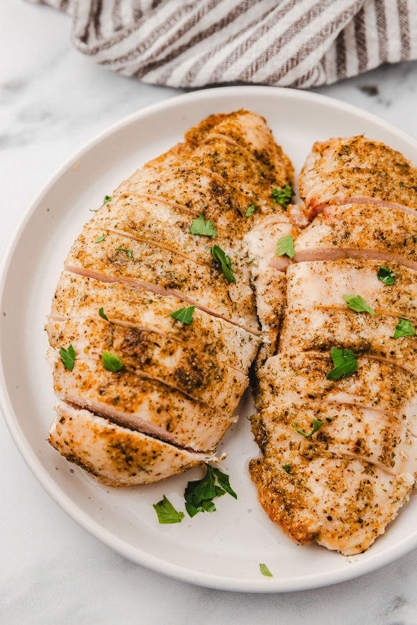 two baked chicken breast slices on a plate. 