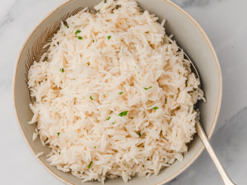 a bowl of garlic rice with spoon in front of an instant pot.