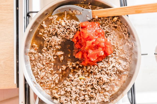 tomato and ground beef and stock cooking in a skillet on the stovetop