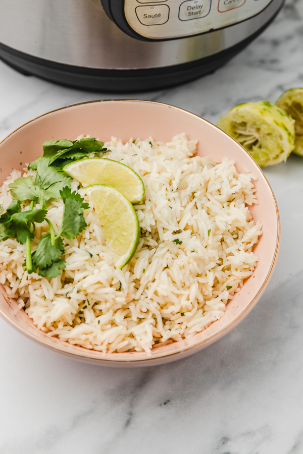 a plate of cilantro lime rice garnished with fresh cilantro leaves and lime slices.