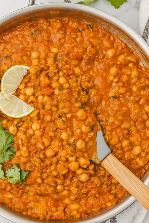 chickpea and lentil in a skillet with silicon ladle.