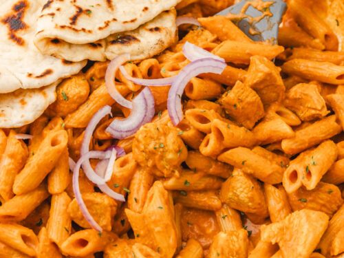 butter chicken pasta and naan bread in a skillet.