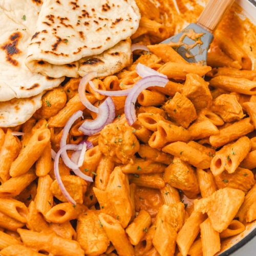 butter chicken pasta and naan bread in a skillet.