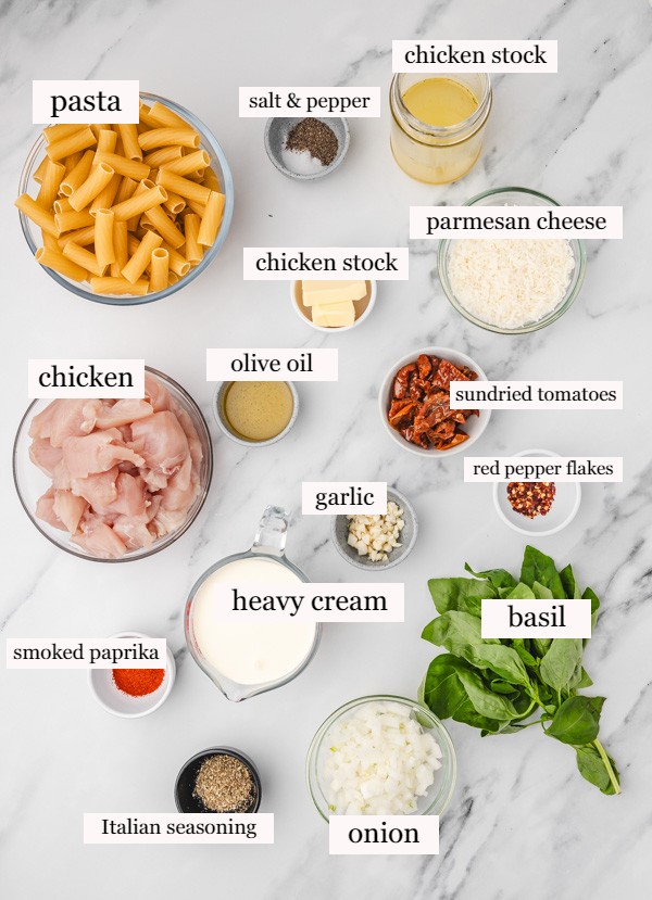 ingredients to make marry me chicken pasta on a white marble surface.