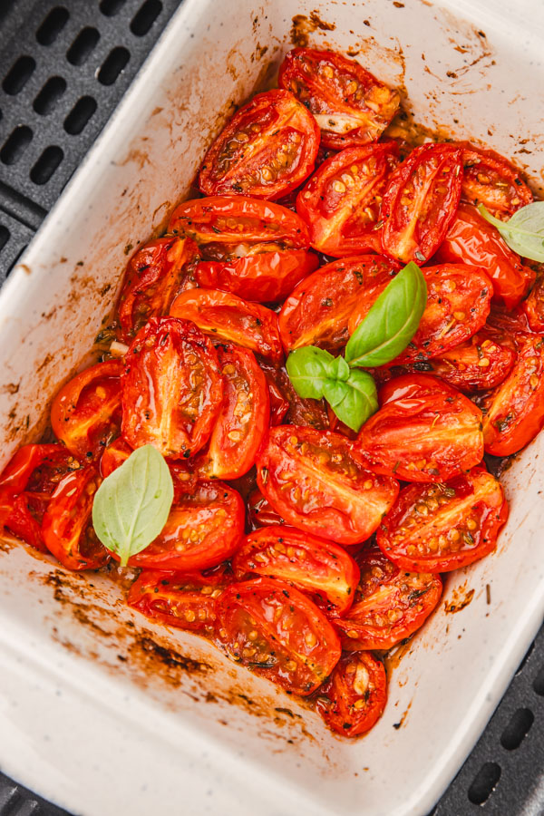 roasted tomatoes in a baking dish in an air fryer basket.