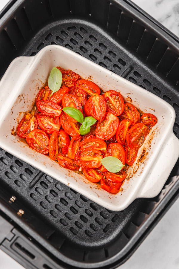 roasted tomatoes cooked in the air fryer garnished with fresh basil.