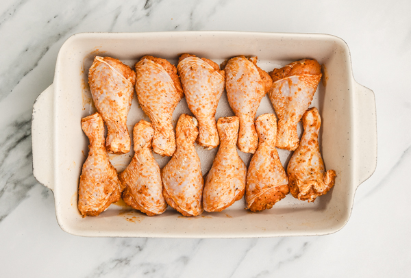 uncooked raw chicken drumsticks in a baking sheet.