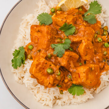 a plate of turkey curry garnished with cilantro leaves.