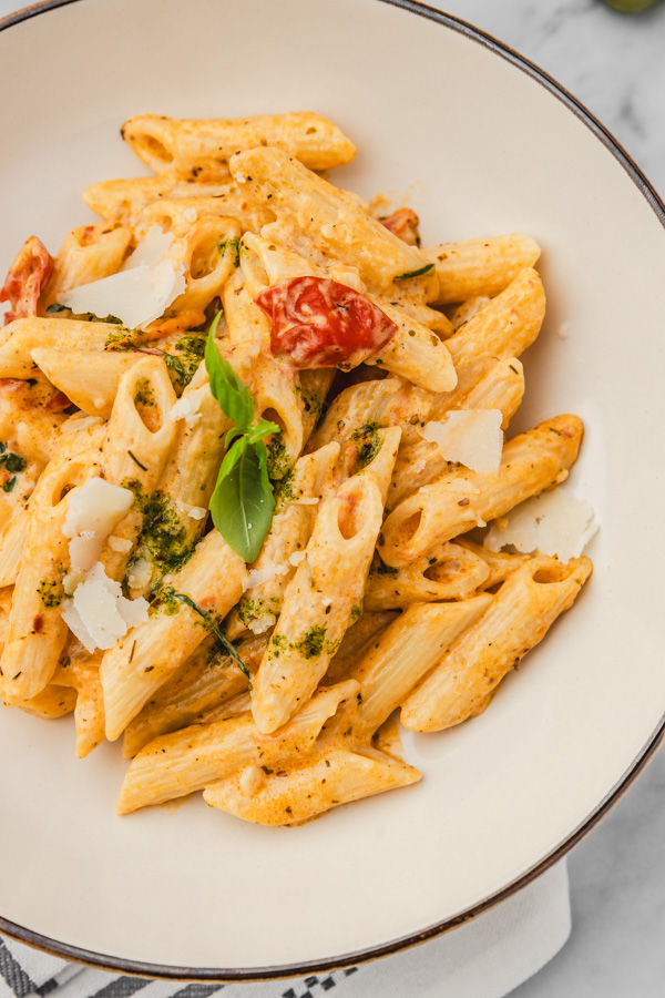 a plate of creamy pasta with tomatoes garnished with fresh basil.
