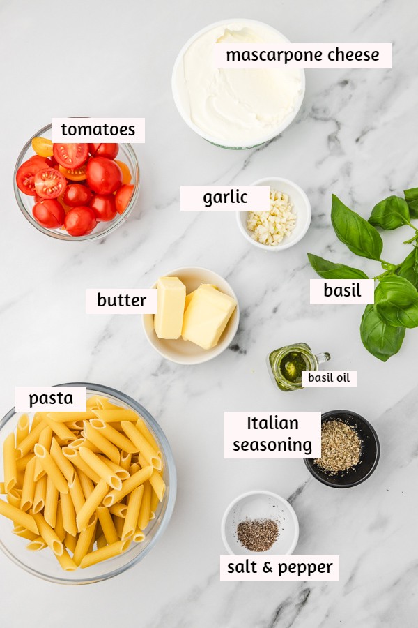 ingredients needed to make mascarpone and tomato pasta on a white marble surface.