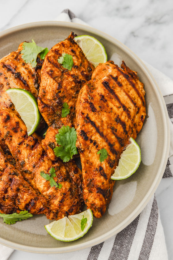 chicken cutlets on a plate garnished with lime wedges.