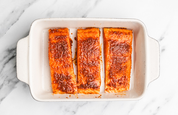 three salmon fillets in a baking dish.