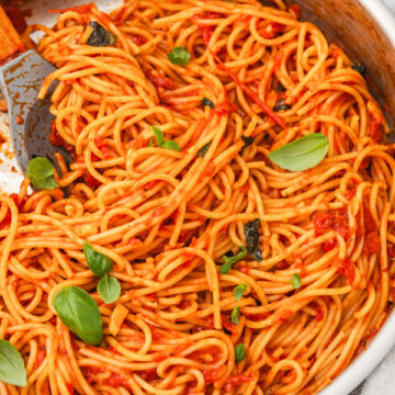 spaghetti arrabiata in a skillet garnished with fresh basil.