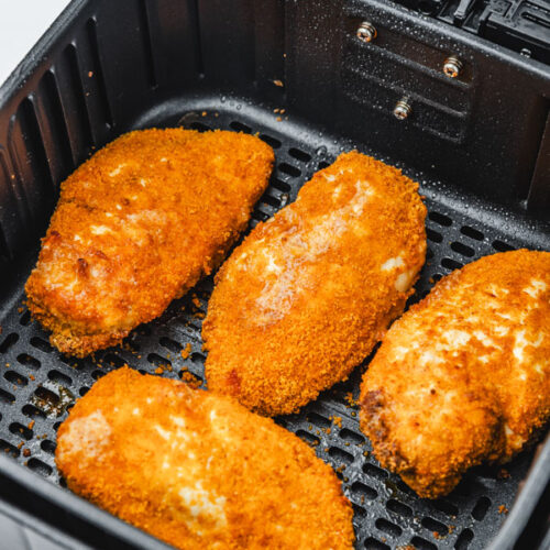 four shake and bake chicken breast in air fryer basket.