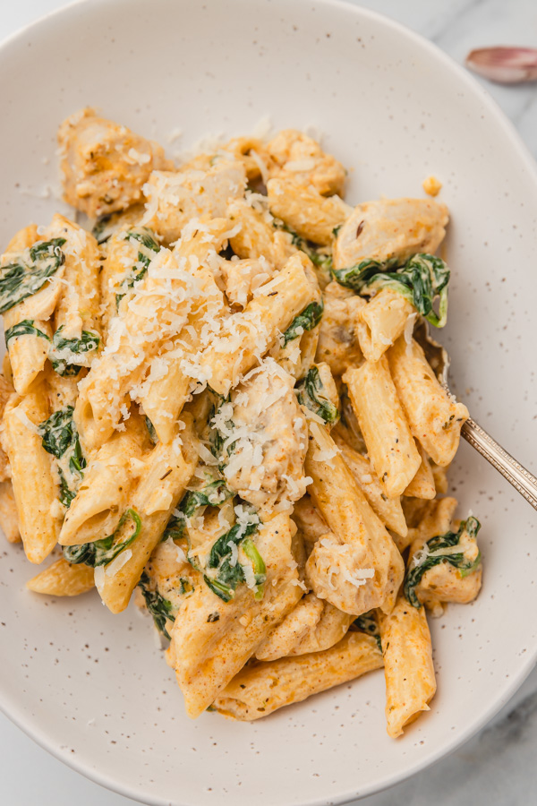 a plate of creamy pasta with spinach garnished with grated parmesan cheese.