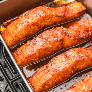 honey soy salmon in a baking pan placed in an air fryer basket.