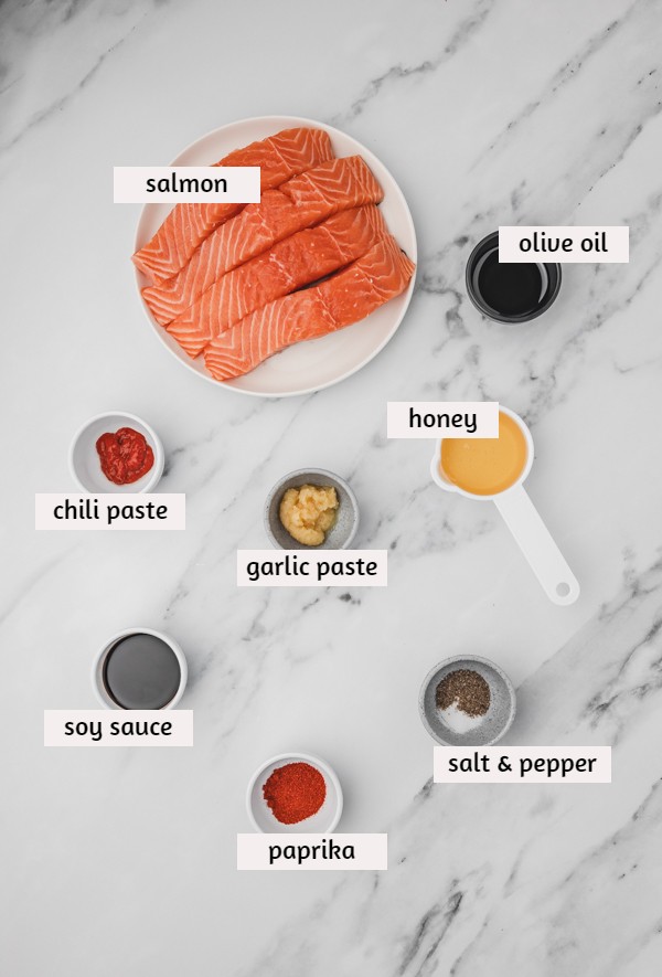 ingredients to make honey soy salmon placed on a white marble surface.