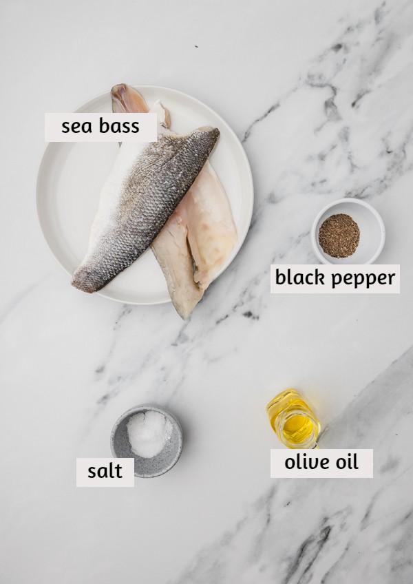 ingredients needed to cook sea bass on a white marble surface.