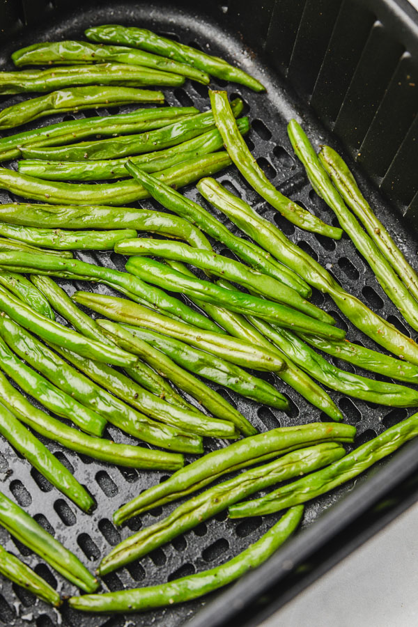 cooked green beans in air fryer basket.