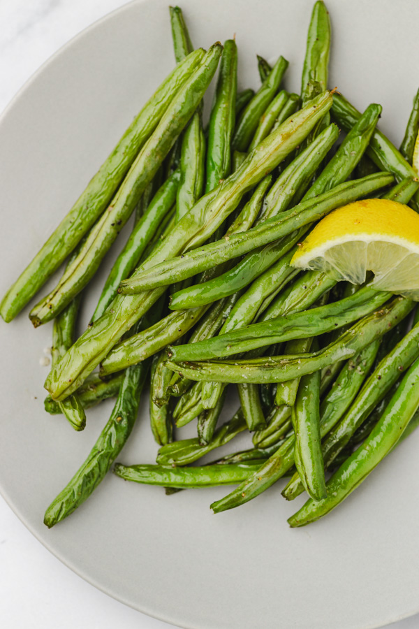green beans and lemon wedge on a plate.