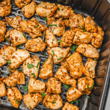 chicken bites garnished with chopped parsley in air fryer basket.
