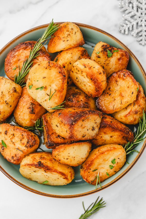 a bowl of roasted potatoes placed beside a snowflake christmas decoration.