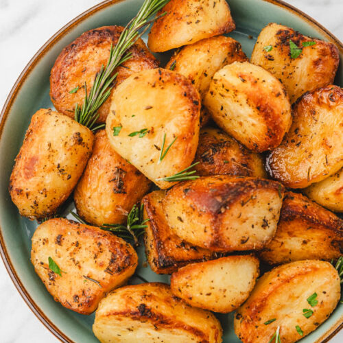 a bowl of crispy and golden brown roast potatoes in a plate.