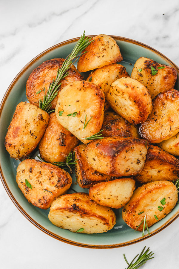 a bowl of crispy and golden brown roast potatoes in a plate.