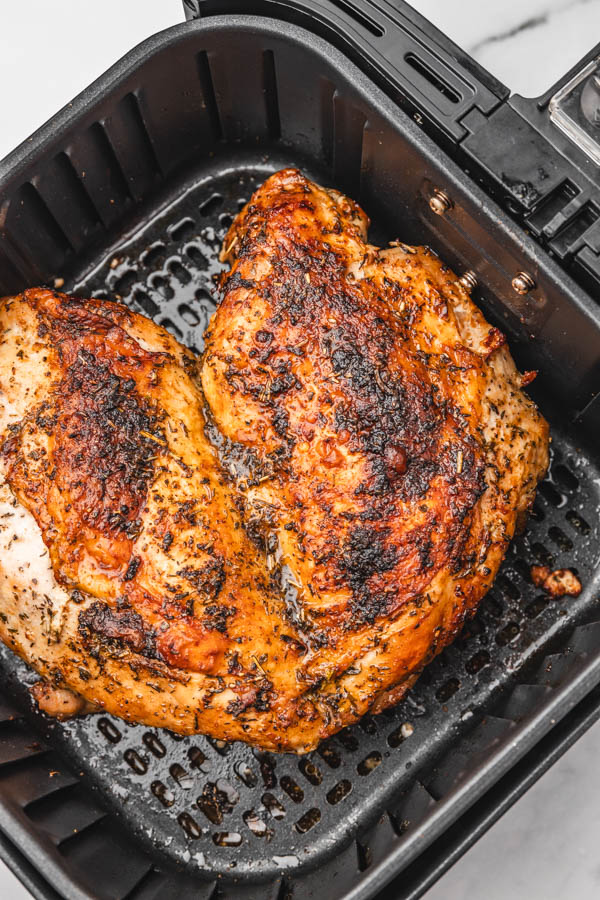 close up of golden brown turkey breast in air fryer basket.