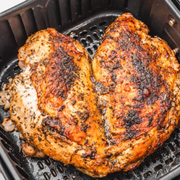 cooked butterflied turkey breast in air fryer basket.