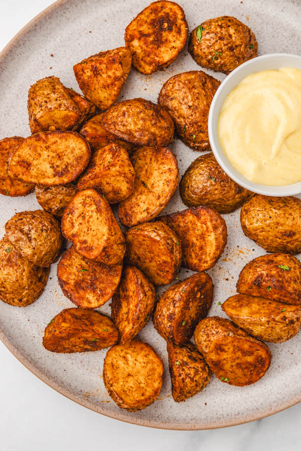 a bowl of seasoned potatoes with a dipping sauce.