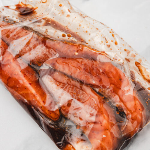 salmon fillets marinating in a ziploc bag on a table.