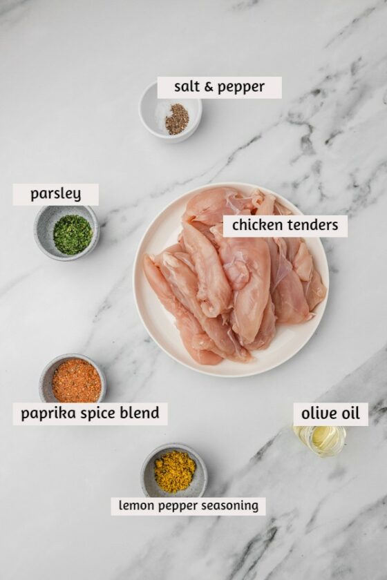 ingredients needed for baked chicken tenderloins laid on a white marble surface.