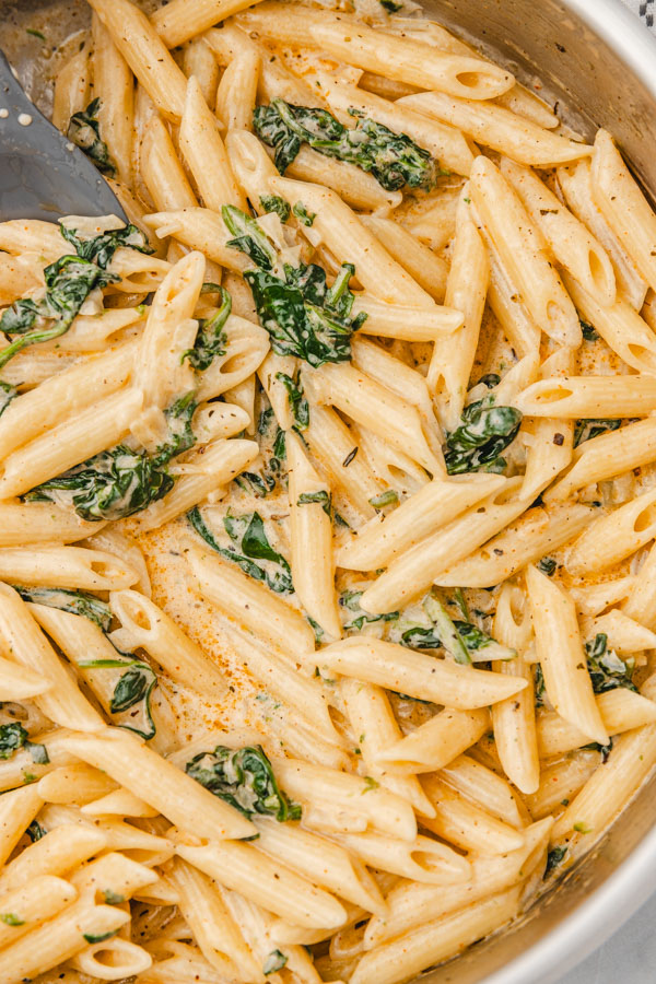 creamy penne pasta with spinach in a skillet.