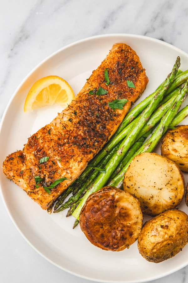 a plate of salmon, asparagus tips and potatoes.