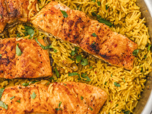 salmon fillets and garlic turmeric rice in a skillet.