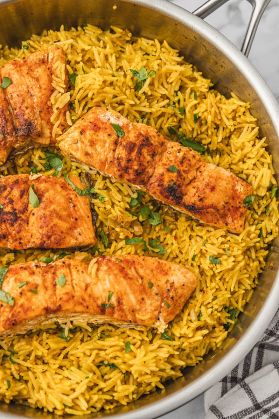 salmon fillets and garlic turmeric rice in a skillet.