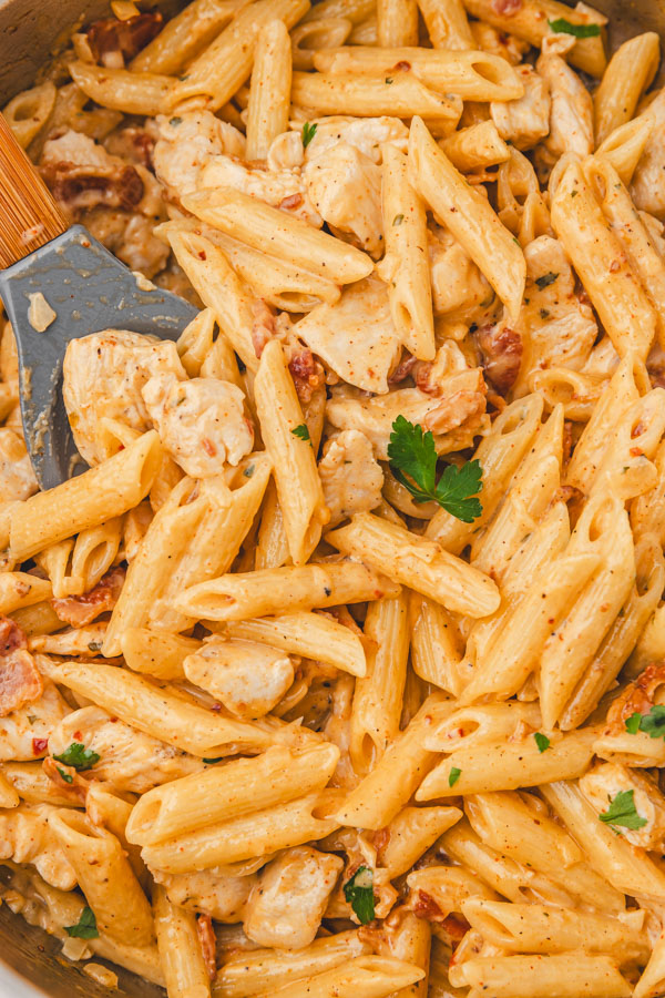 a close up of creamy penne pasta in a skillet.