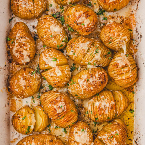 mini hasselback potatoes in a baking dish garnished with chopped parsley.
