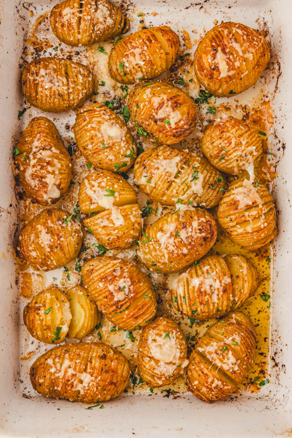 mini hasselback potatoes in a baking dish garnished with chopped parsley.