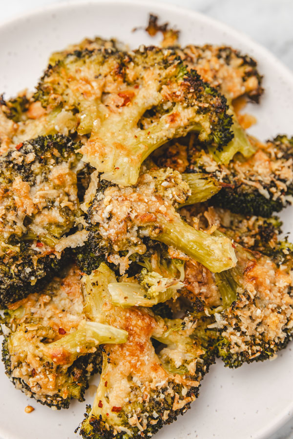 a close up of smashed broccoli florets on a plate.